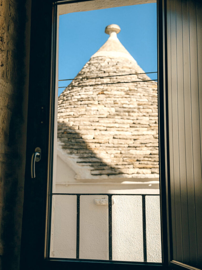 Il cono di un trullo visto dalla porta-finestra della camera